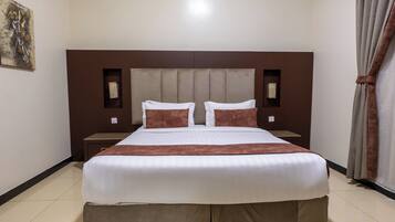 A hotel room with a large bed, two bedside tables, a headboard, and a painting on the wall.