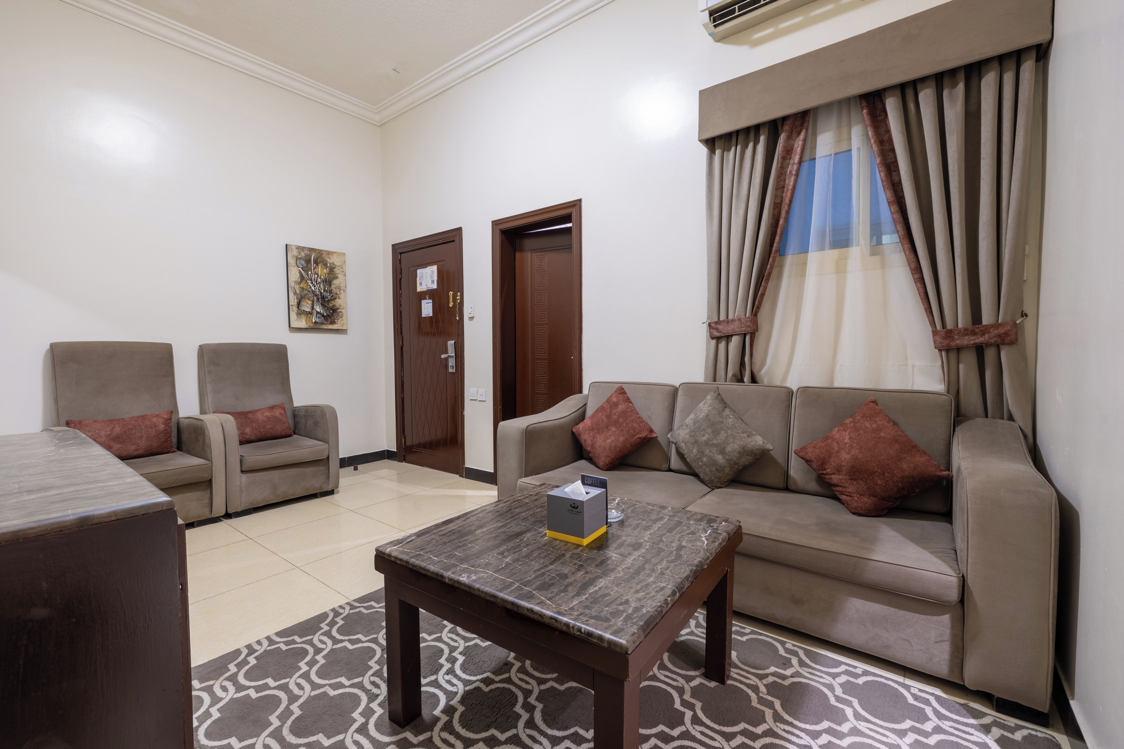 A living room with a sofa, two armchairs, a coffee table, and a patterned rug.