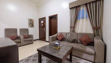 A living room with a sofa, two armchairs, a coffee table, and a patterned rug.