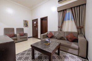 Uma sala de estar com sofá, duas poltronas, mesa de centro e tapete estampado.