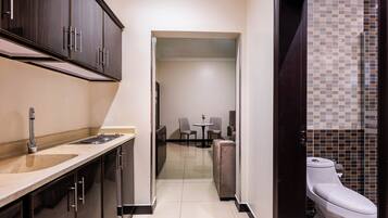 A compact hotel room with a kitchenette, a dining area, and a bathroom.