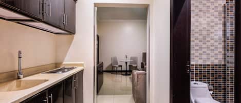 A compact hotel room with a kitchenette, a dining area, and a bathroom.