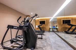 A gym with exercise equipment, a mirrored wall, and a wooden wall with a television.