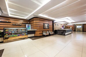Eine moderne Hotelhalle mit Verkaufsautomaten, einer Sitzecke und einer Rezeption.