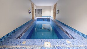 A swimming pool with a geometric tile pattern, a shower area, and a door leading to another room. - Al Muhaidb Residence Al ASKARY - Economic (Riyadh)