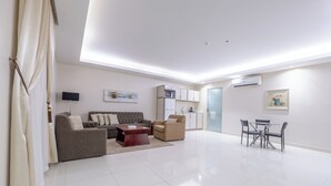 A modern living room with a sofa, armchair, coffee table, and dining table. - Al Muhaidb Residence Al ASKARY - Economic (Riyadh)