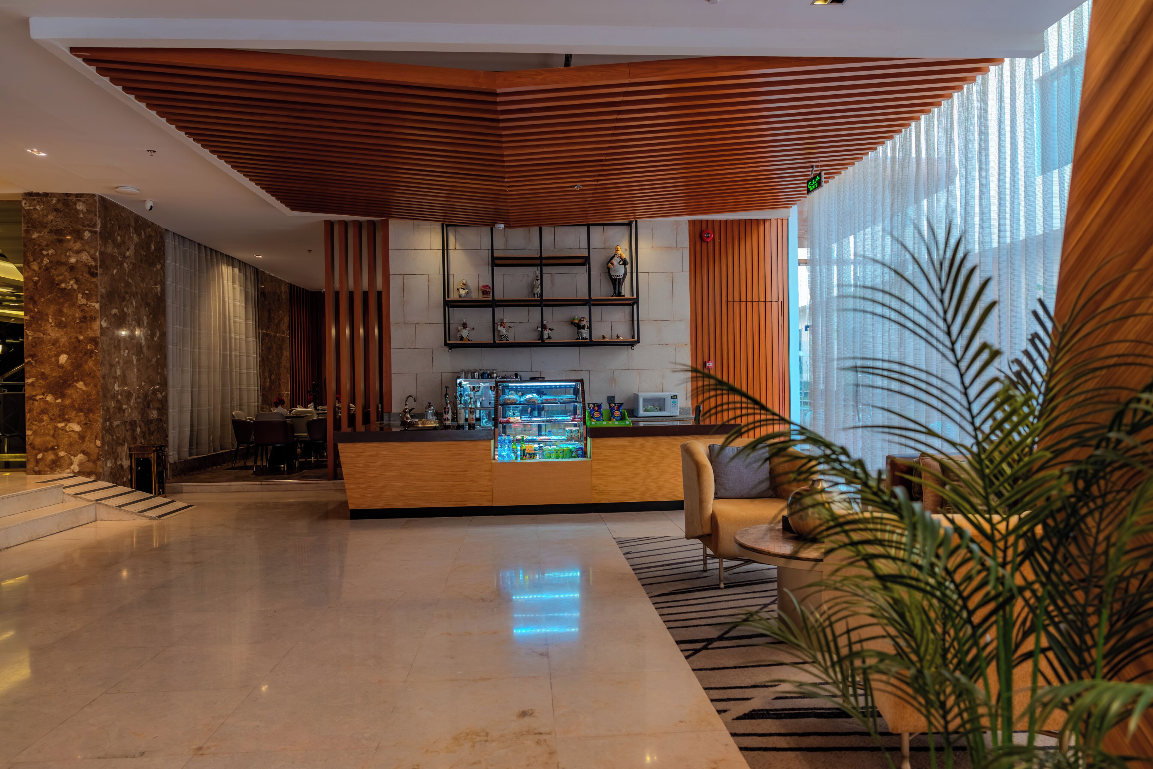 A modern lobby with a reception desk, a seating area, and a large window with curtains.