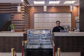 A hotel reception area with a modern design, featuring a wooden panel wall, a glass display case with beverages, and a staircase in the background. - Al Muhaidb Residence Al Malaz 5 - Economic (Riyadh)