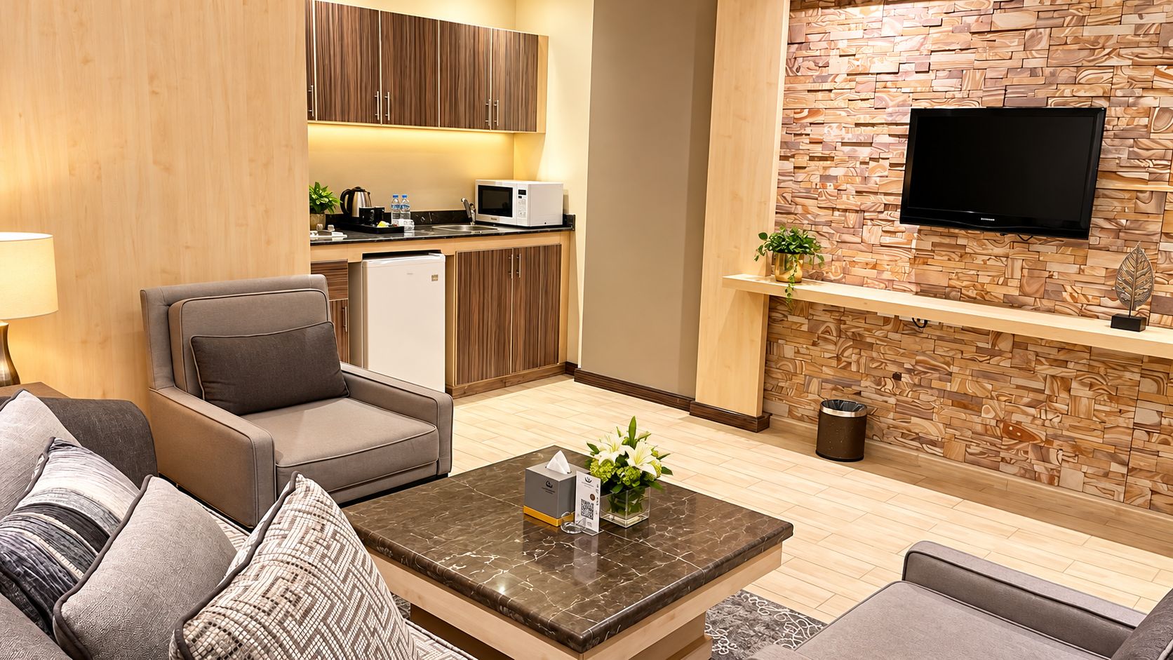 A modern living room with a sofa, armchair, and a coffee table with a vase of flowers.