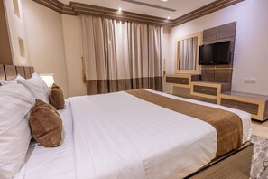 A modern bedroom with a large bed, a TV, and a built-in desk. - Al Muhaidb Residence Al Malaz 5 - Economic (Riyadh)