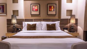 A hotel room with a large bed, two bedside lamps, a telephone, and framed artwork on the wall.