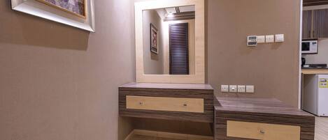 Un baño con tocador de madera, un espejo y un cuadro en la pared.
