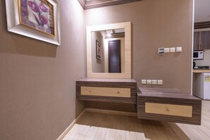 A bathroom with a wooden vanity, a mirror, and a framed picture on the wall. - Al Muhaidb Residence Al Malaz 5 - Economic (Riyadh)