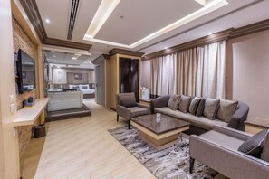 A modern living room with a sofa, armchairs, a coffee table, and a television. - Al Muhaidb Residence Al Malaz 5 - Economic (Riyadh)