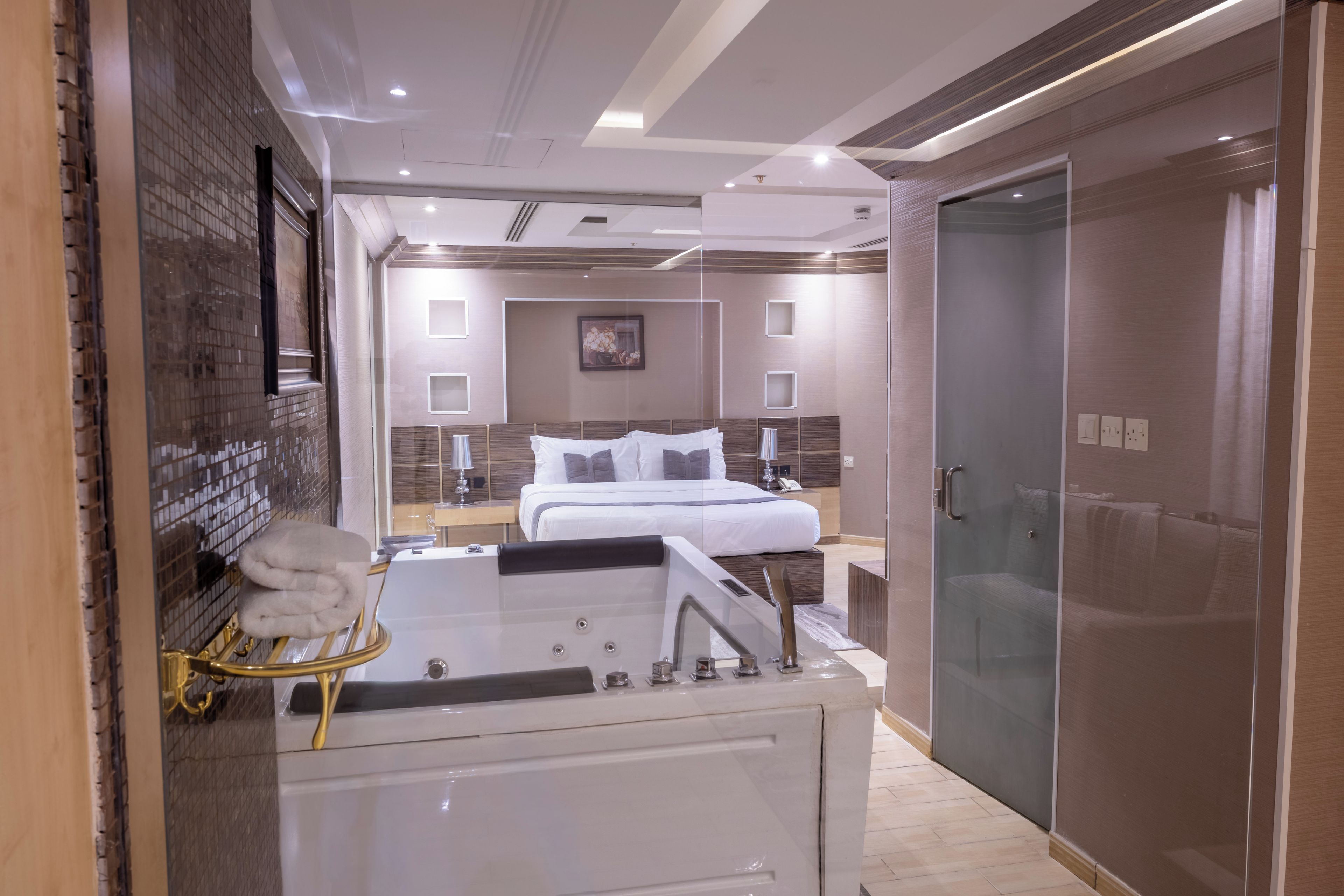 Ein modernes Hotelzimmer mit einem großen Bett, einer separaten Sitzecke und einer Duschkabine aus Glas.