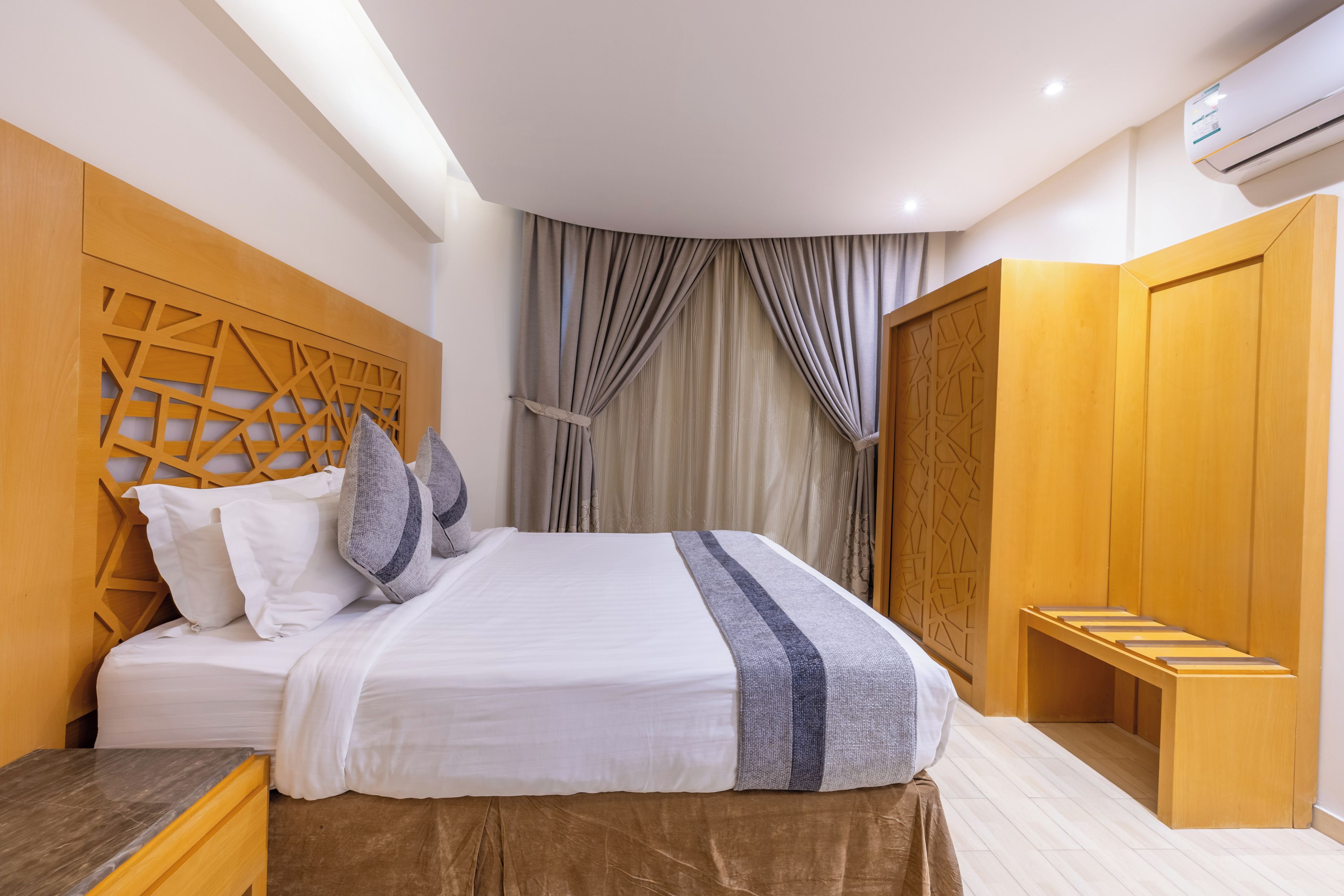A modern bedroom with a bed, wooden headboard, and a wardrobe.