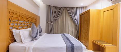 Un dormitorio moderno con cama, cabecero de madera y armario.