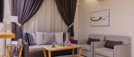 A modern living room with a sofa, armchairs, a coffee table, a lamp, and an air conditioning unit.