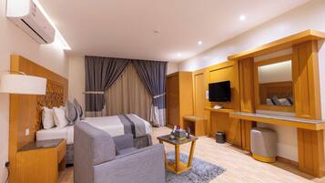 Una habitación de hotel con cama, sofá, televisor, una mesita y un espejo.