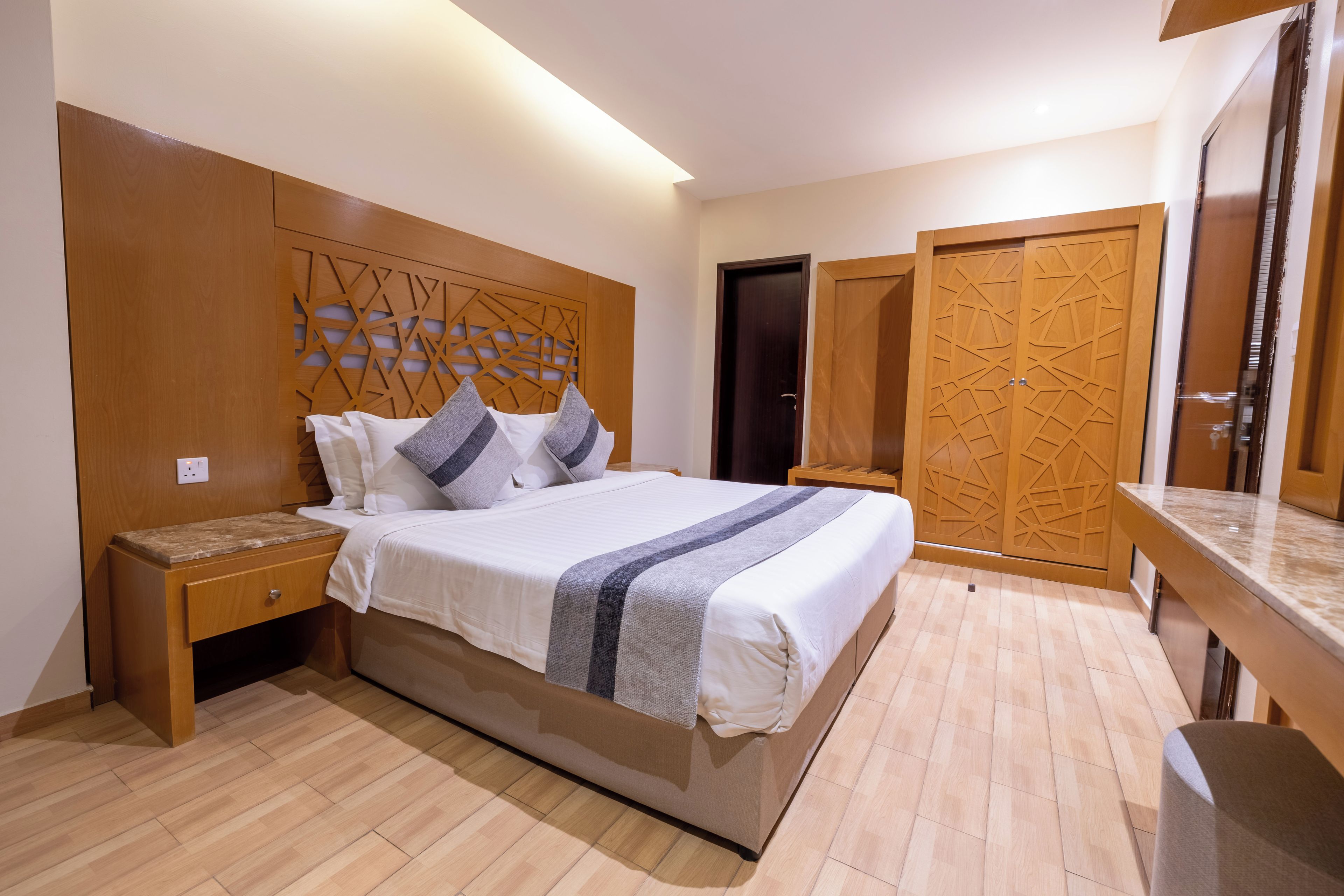 A bedroom with a bed, nightstands, a dresser, and a wardrobe.