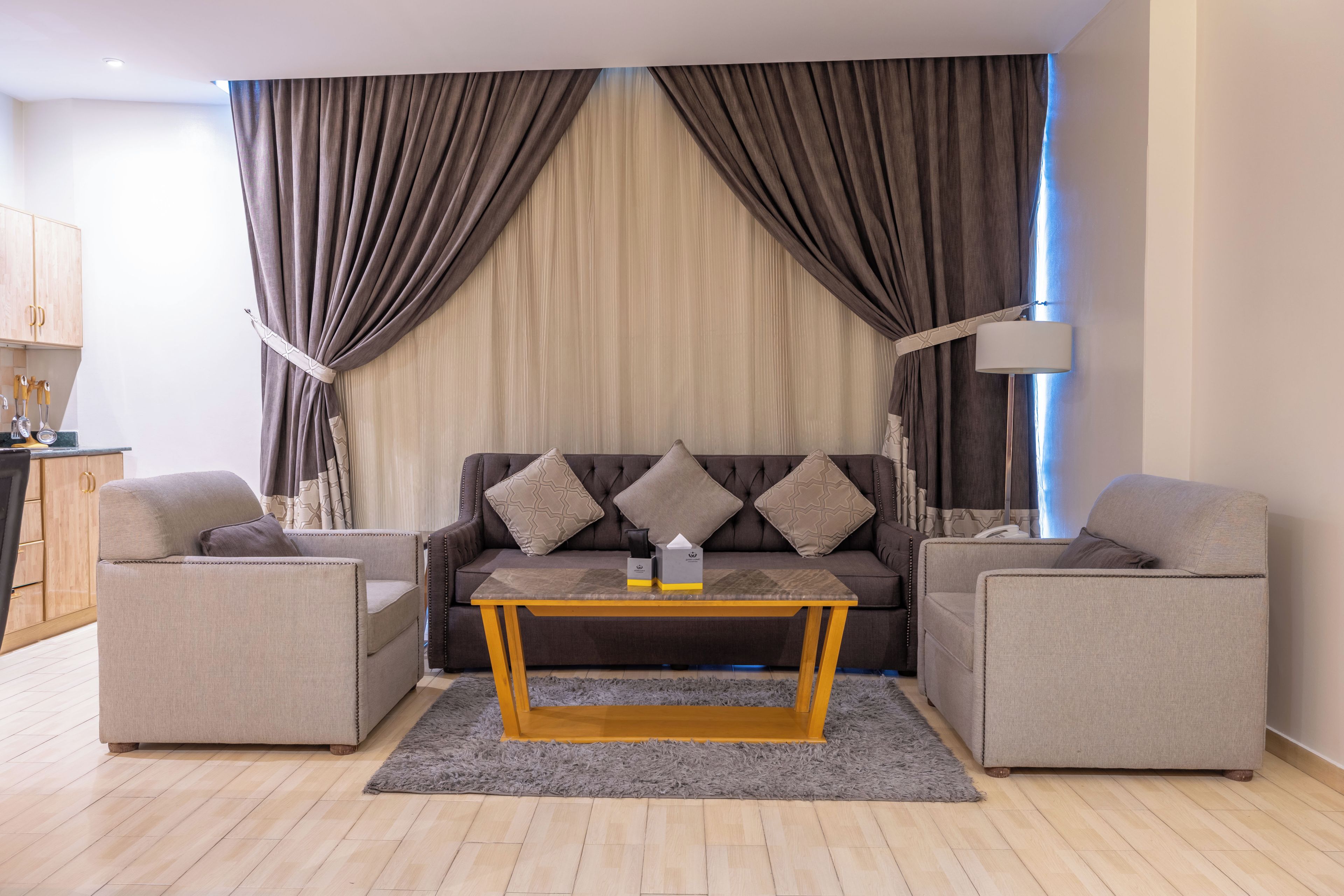 Ein Wohnzimmer mit einer Couch, zwei Sesseln, einem Couchtisch und einer Lampe.
