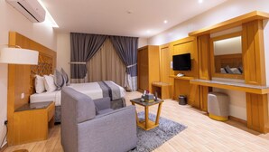 A hotel room with a bed, a sofa, a TV, a small table, and a mirror.