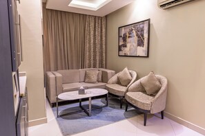 A modern living room with a sofa, two armchairs, a coffee table, and a painting on the wall. - Al Muhaidb Residence Al Takhasossi 2 - Economic (Riyadh)