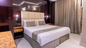A modern hotel room with a large bed, wooden nightstands, and a marble side table.