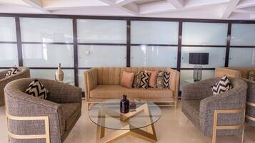 A modern lounge area with a sofa, armchairs, and a glass coffee table.