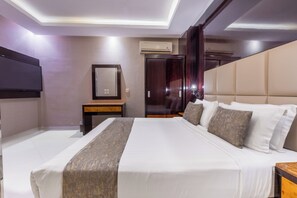 A hotel room with a large bed, a flat-screen TV mounted on the wall, a small table, and a wardrobe. - Al Muhaidb Residence Al Takhasossi 2 - Economic (Riyadh)