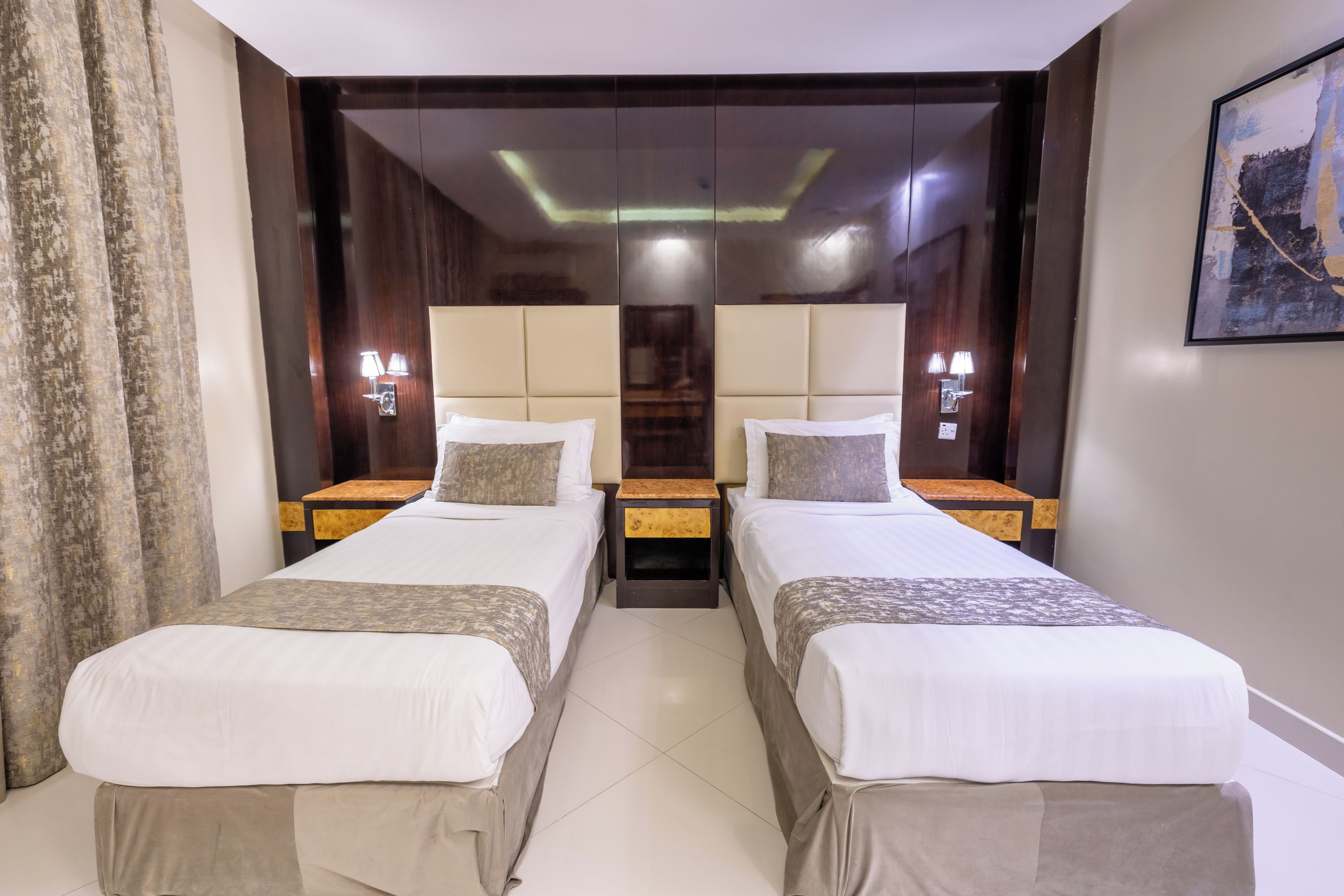 A hotel room with two beds, a large mirror, and a painting on the wall.