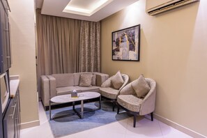 Uma sala de estar moderna com sofá modular, duas poltronas, uma mesa de centro e um quadro na parede.