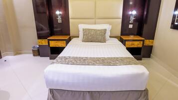 A hotel room with a large bed, two bedside tables, and a nightstand with a lamp.