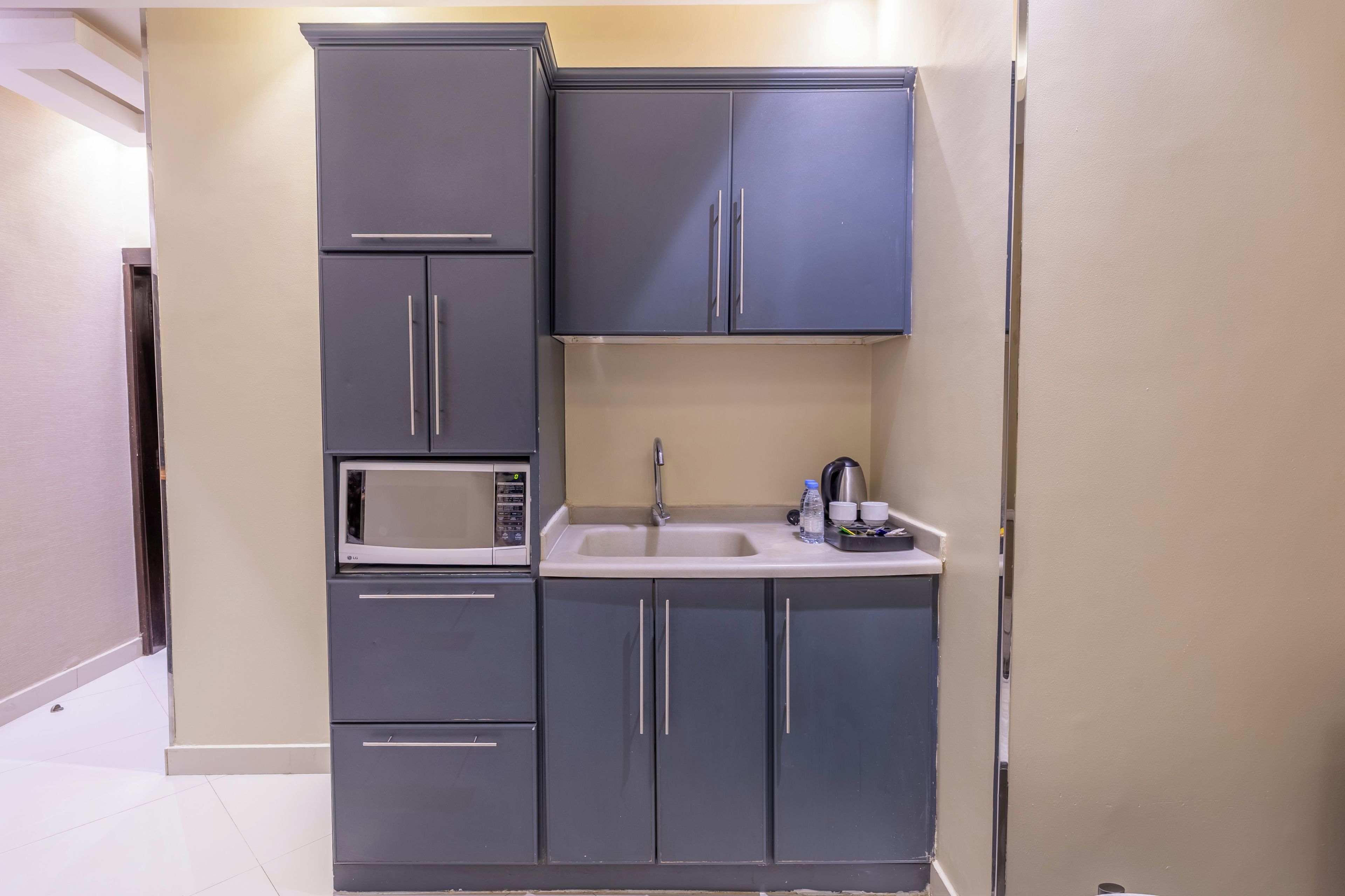 Una cocina compacta con microondas, lavamanos y armarios.