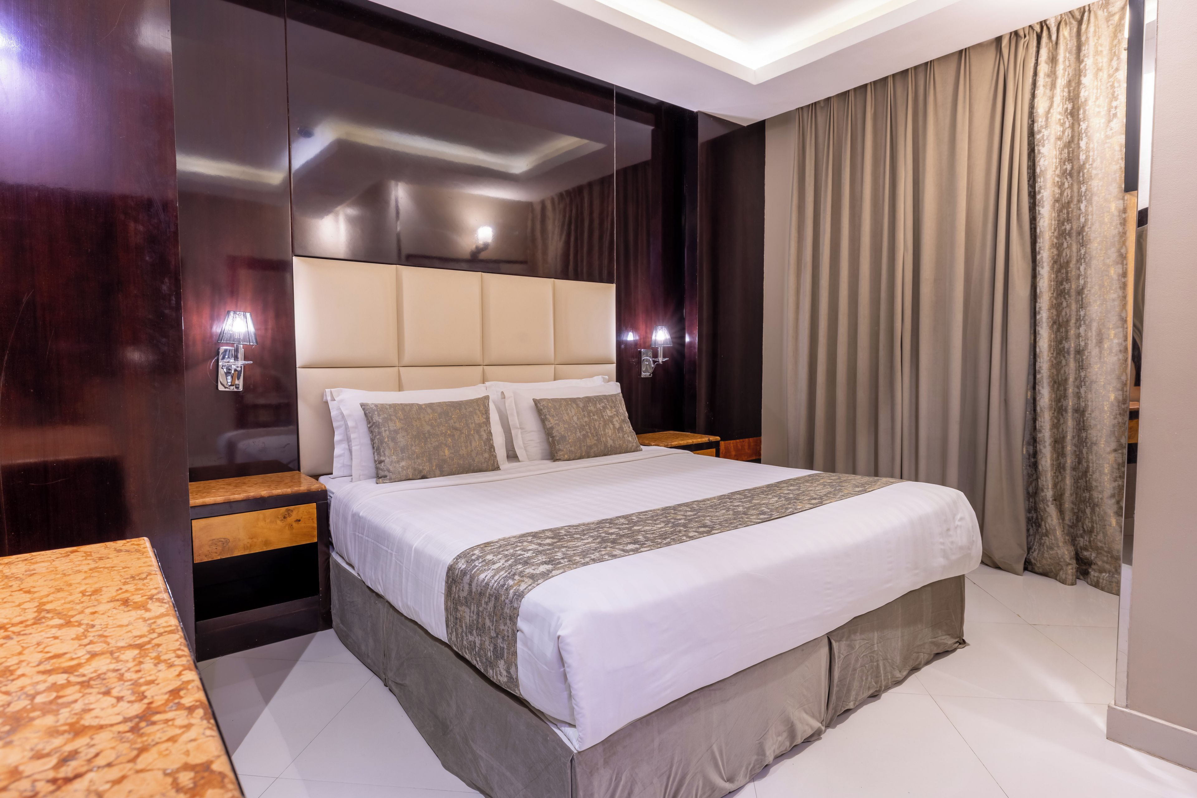 Une chambre d’hôtel moderne avec un grand lit, des tables de chevet et une tête de lit.