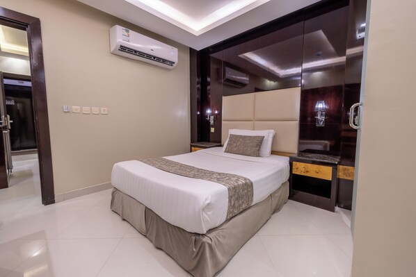 A modern hotel room with a large bed, a built-in wardrobe, and an air conditioning unit. - Al Muhaidb Residence Al Takhasossi 2 - Economic (Riyadh)