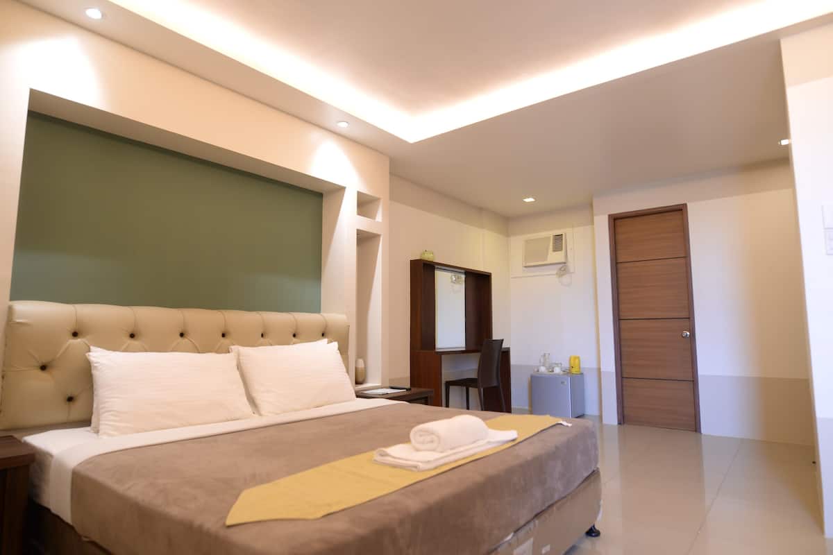 Quarto de hotel moderno com uma cama grande, uma escrivaninha, uma cadeira e um guarda-roupa.