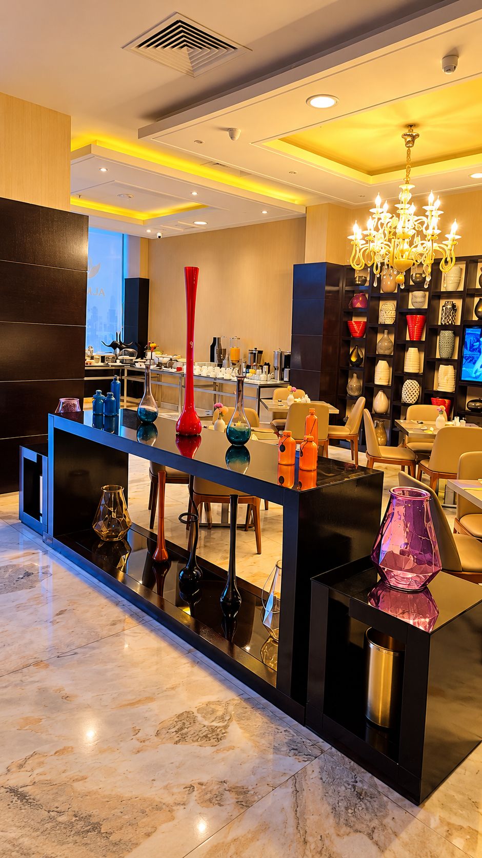 A modern interior with a marble floor, a central bar area with a reflective surface, and a decorative chandelier.