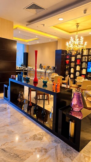 A modern interior with a marble floor, a central bar area with a reflective surface, and a decorative chandelier. - Al Muhaidb Residence Al JAWAZAT  1 - Economic (Riyadh)
