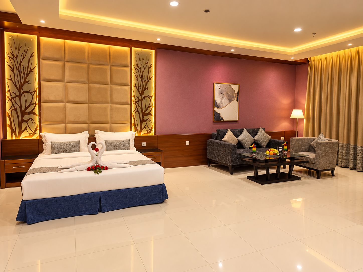 A hotel room with a large bed, a sofa, a coffee table, and a lamp.