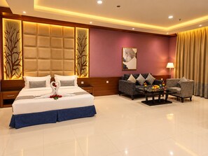 A hotel room with a large bed, a sofa, a coffee table, and a lamp. - Al Muhaidb Residence Al JAWAZAT  1 - Economic (Riyadh)