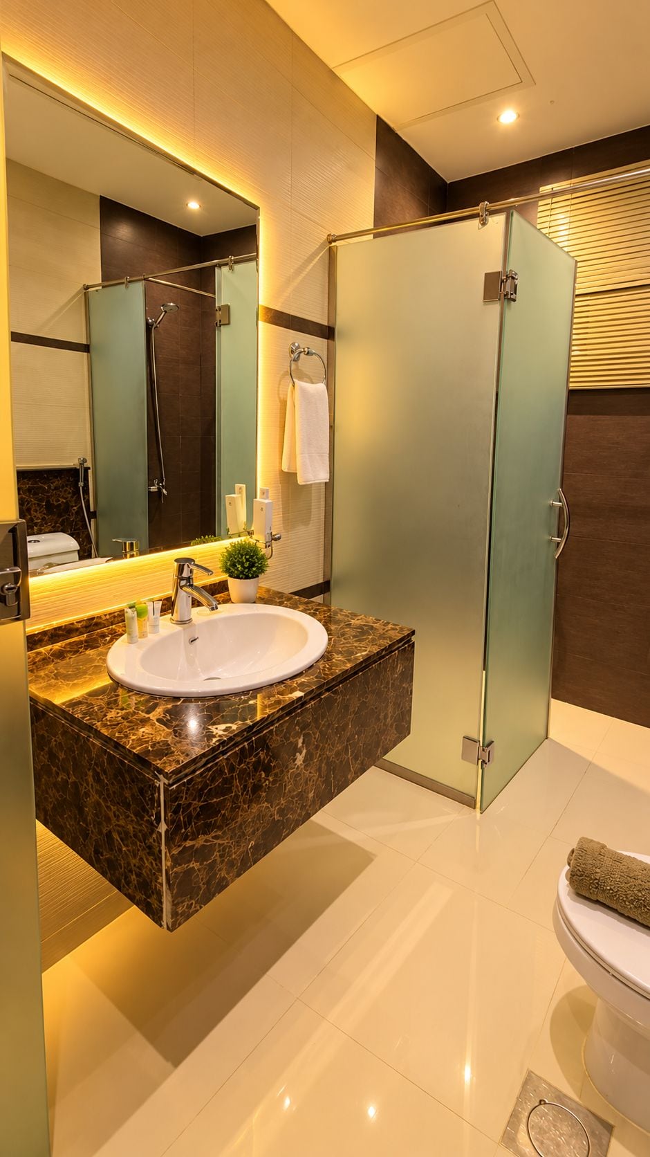 Une salle de bain moderne avec un lavabo en marbre, une cabine de douche en verre et des toilettes.