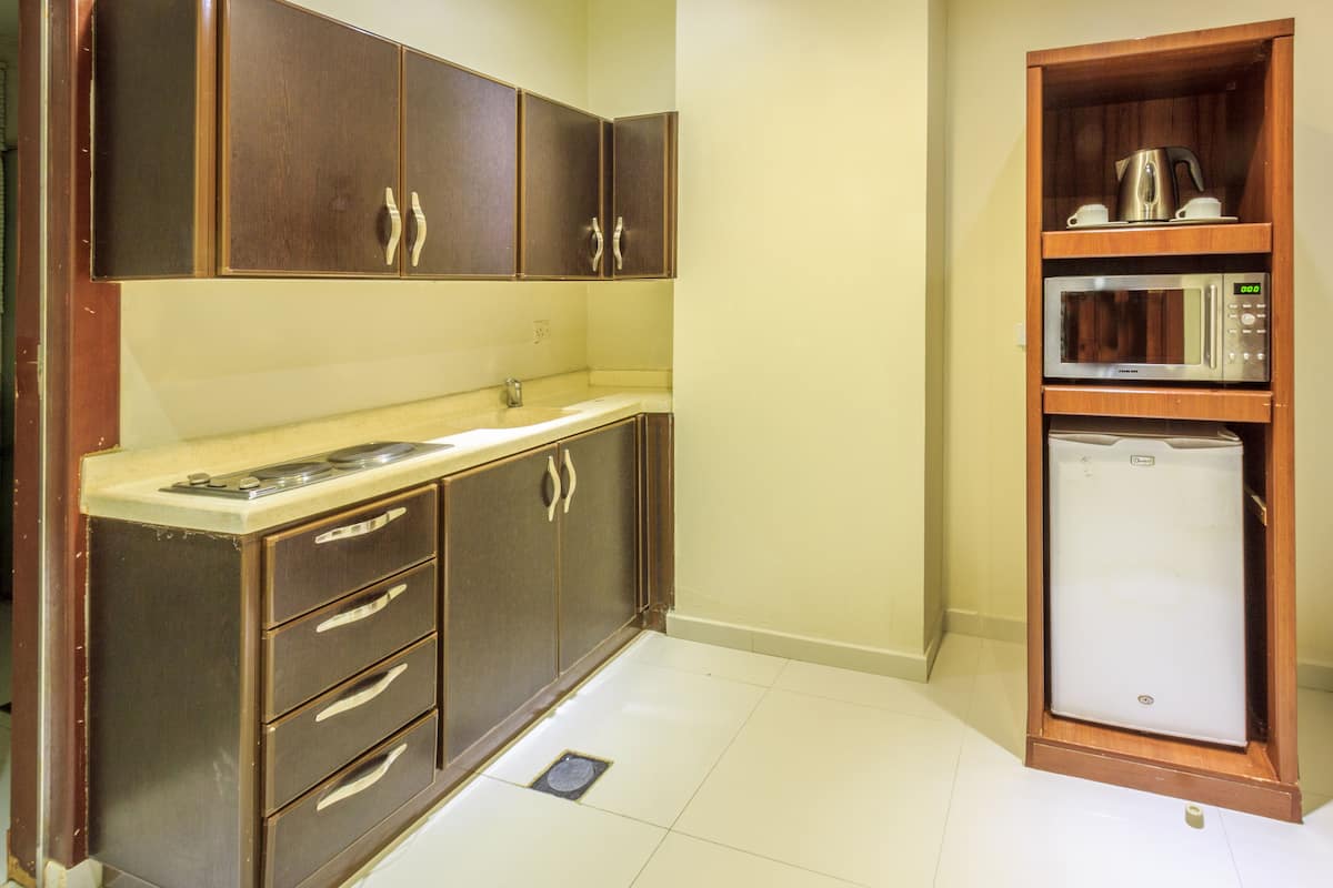 A compact kitchen with dark wooden cabinets, a countertop, and a built-in microwave.