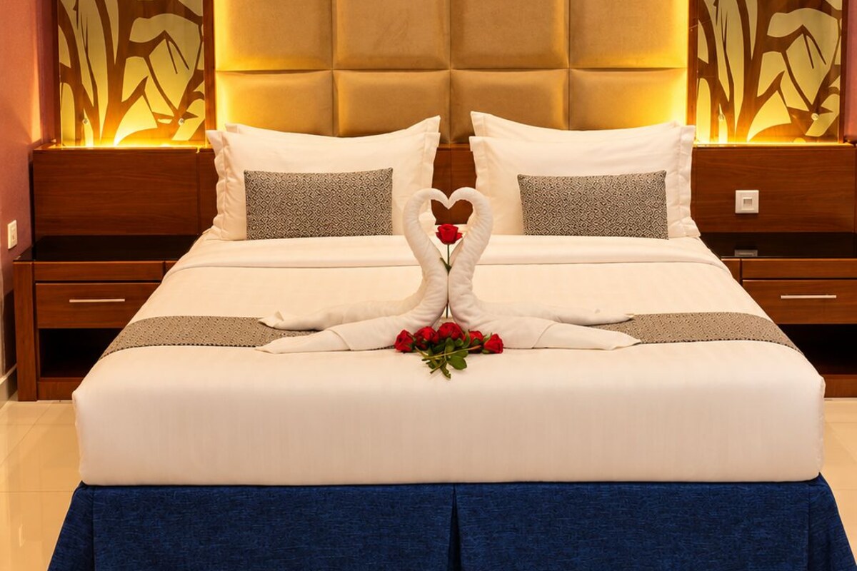 A hotel room with a large bed, a headboard with a padded design, and decorative wall panels.