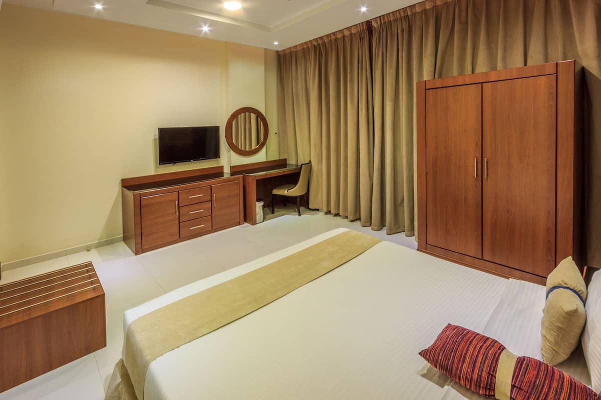 A hotel room with a bed, a desk, a TV, and a wardrobe.