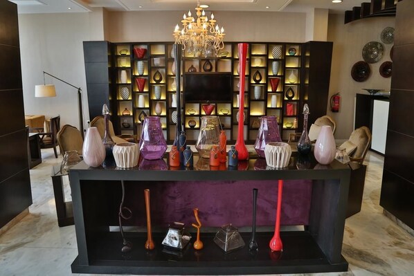 A modern interior with a black console table displaying various glass vases and a chandelier above. - Al Muhaidb Residence Al JAWAZAT  1 - Economic (Riyadh)