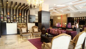 A lobby with a reception desk, seating area with armchairs and sofas, a chandelier, and a display of decorative items. - Al Muhaidb Residence Al JAWAZAT  1 - Economic (Riyadh)