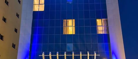 A hotel with a modern facade, illuminated signage, and a well-lit entrance area.