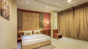A spacious hotel bedroom with a large bed, a nightstand, a bedside table, and a view of the outside through a window with curtains. - Al Muhaidb Residence Al JAWAZAT  1 - Economic (Riyadh)