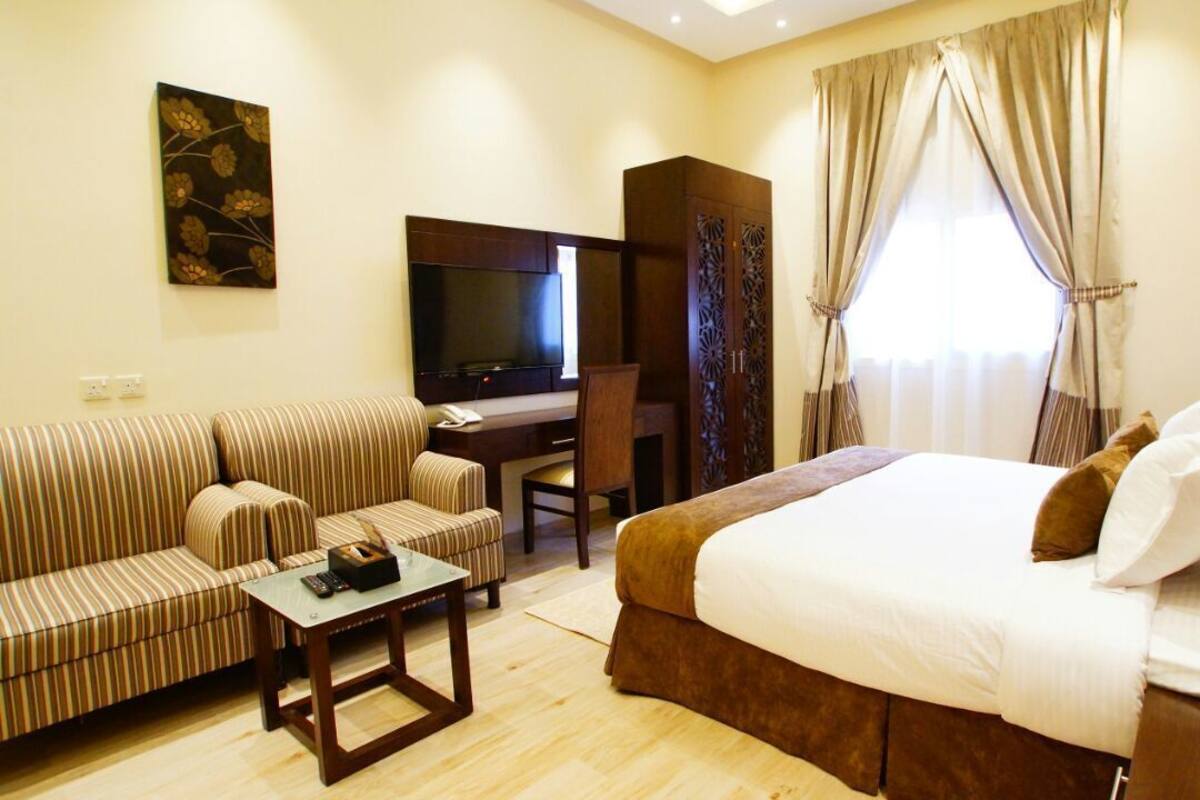 Une chambre d’hôtel comprenant un lit, un canapé, une télévision, un bureau et une armoire.